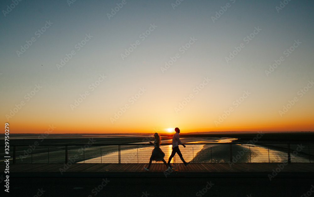 Couple walking next to a river during sunset
