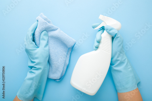 Obraz na plátne Hands in rubber protective gloves holding white spray bottle and rag