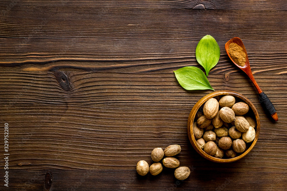 Nutmeg - spices in powder and whole nuts - on wooden background top-down copy space