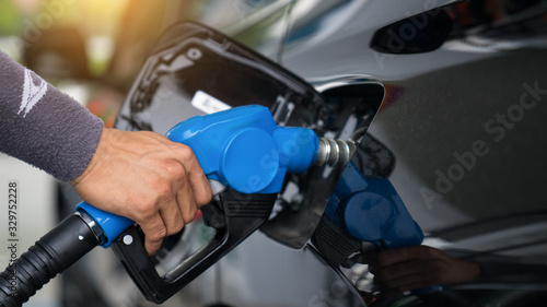 Pumping gas at gas pump. Closeup of man pumping gasoline fuel in car at gas station.