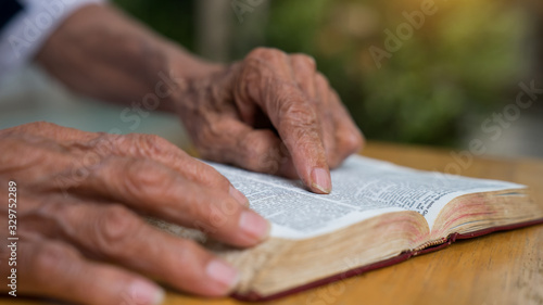 Old man reading her bible while sitting outside