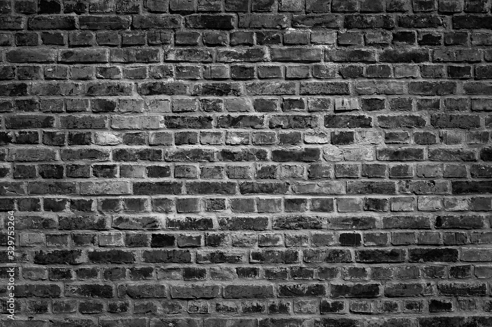 Fototapeta premium An old black bricks wall surface abstract pattern background. Background of old vintage brick wall with vignetting.