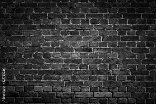 An old black bricks wall surface abstract pattern background. Background of old vintage brick wall with vignetting.