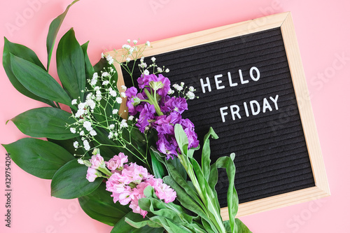 Hello Friday text on black letter board and bouquet colorful flowers on pink background. Concept Happy Friday. Template for postcard, greeting card Flat lay Top view