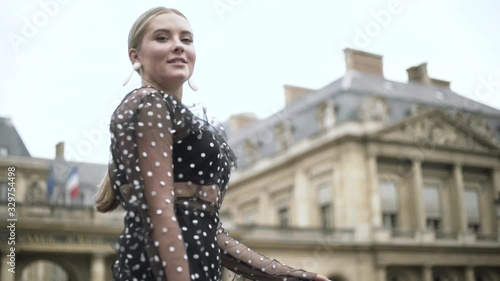 Stylish European woman wearing black dotted sexy dress and white small purse, Paris, France. Action. Blond plus size model walking in the street. photo
