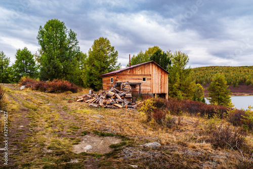 Wooden bath with a stack of firewood on the lake Uzunkel. Ulagansky District, Altai Republic, Russia
