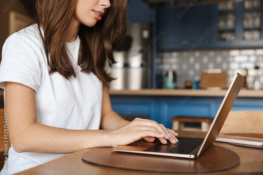 Cropped image of young brunette woman typing on laptop Cropped image of young brunette woman typing on laptop