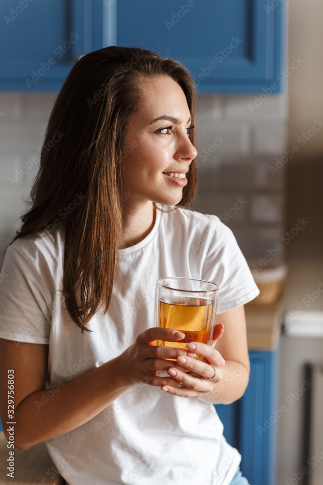 Image of smiling beautiful woman looking aside and drinking tea Image of smiling beautiful woman looking aside and drinking tea