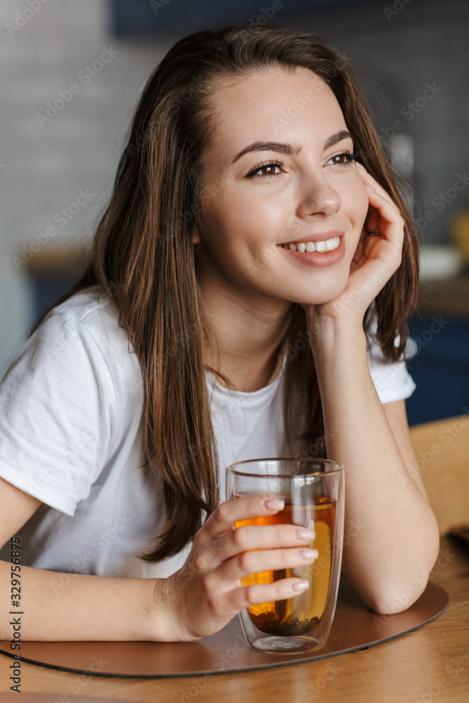 Image of cheerful beautiful woman smiling and drinking tea Image of cheerful beautiful woman smiling and drinking tea