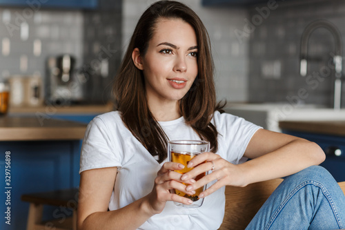 Image of pleased beautiful woman smiling and drinking tea