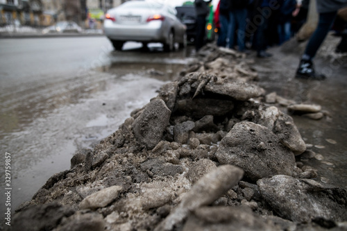 people are standing at a bus stop, getting on a bus stepping over uncleared snow and mud, special services do not clean the city