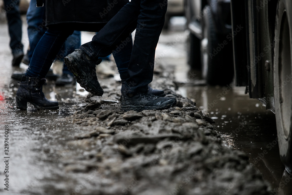 people are standing at a bus stop, getting on a bus stepping over uncleared snow and mud, special services do not clean the city people are standing at a bus stop, getting on a bus stepping over uncleared snow and mud, special services do not clean the city