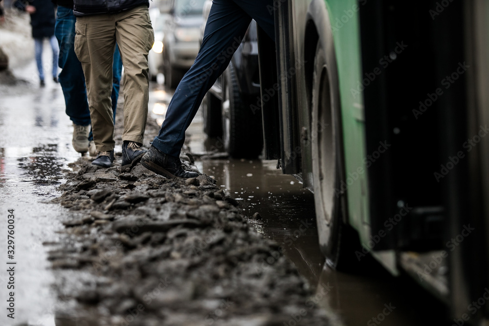 people are standing at a bus stop, getting on a bus stepping over uncleared snow and mud, special services do not clean the city people are standing at a bus stop, getting on a bus stepping over uncleared snow and mud, special services do not clean the city