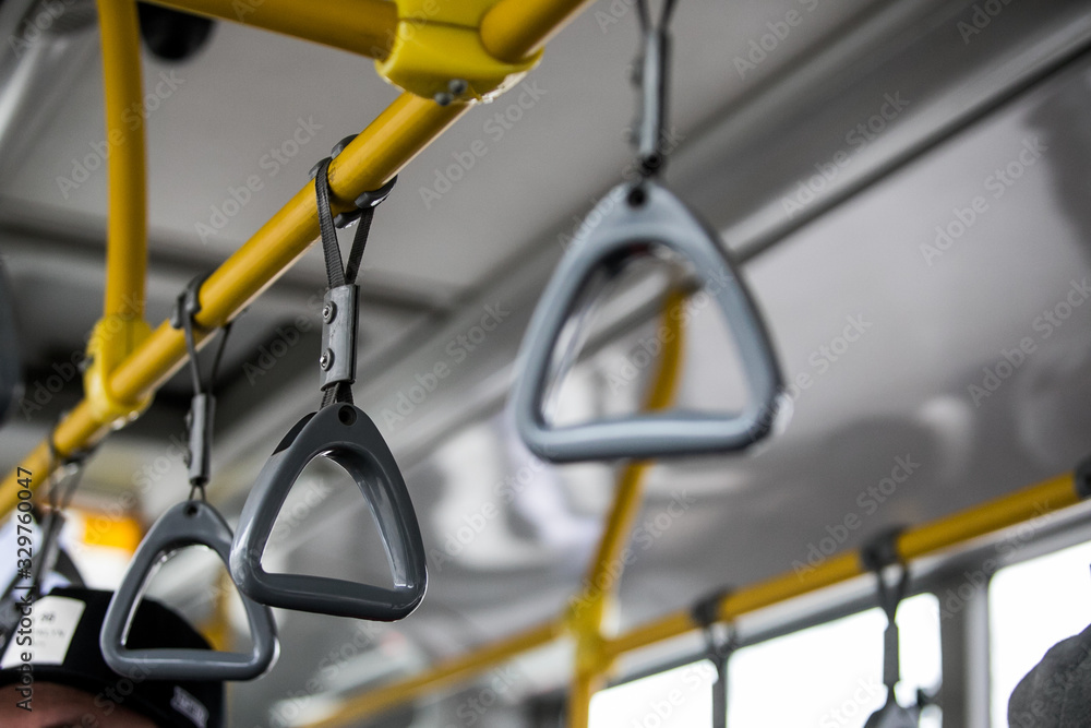 Yellow handles on ceiling rails for standing passenger. Handle on the MRT, prevent toppling.underground railway system or metro,people holding onto a handle on a train and the bus. Selective focus