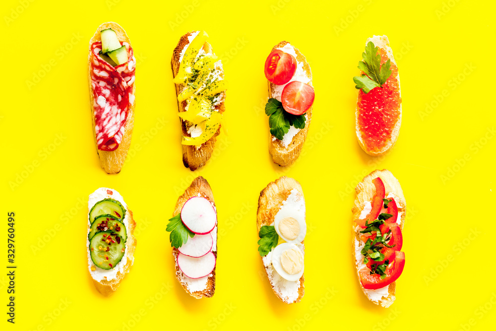 Fototapeta premium Sandwiches assorti pattern on yellow background top-down