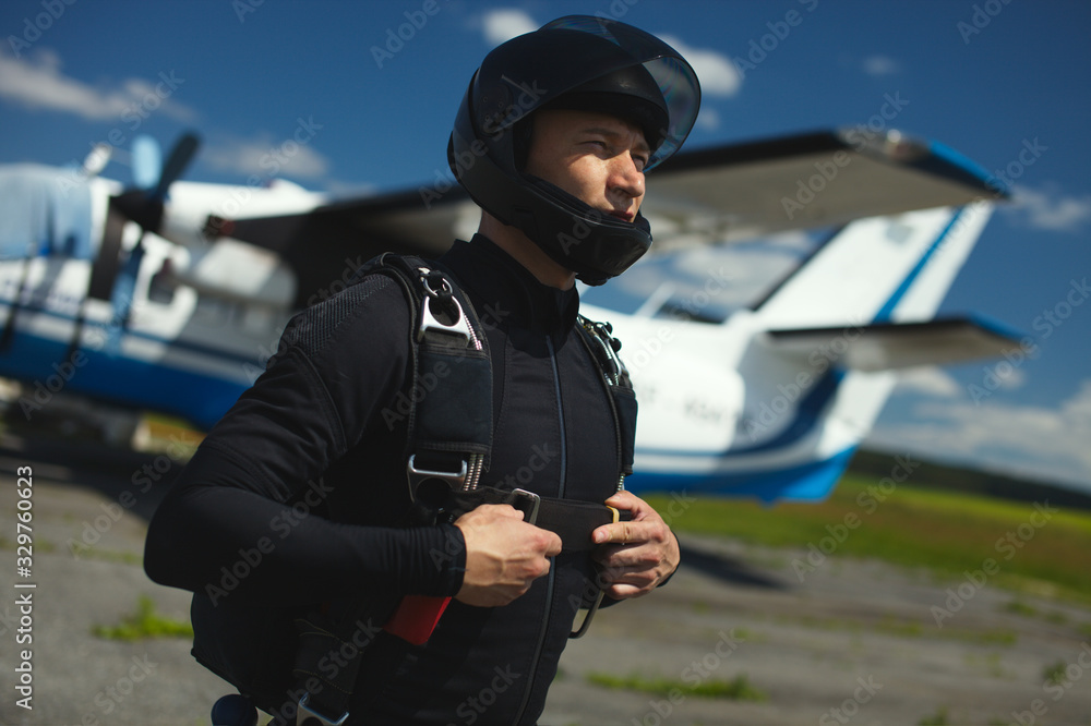 Skydiver in a helmet with a parachute against the background of an airplane, close-up. Skydiver in a helmet with a parachute against the background of an airplane, close-up.