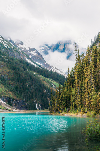 Landscape view of Lake Louise in Banff National Park on a foggy misty day with pine trees and mountains partly covered with ice