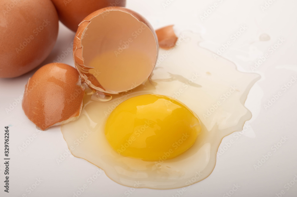 Broken chicken egg and eggs scattered on a white background. Close up. Broken chicken egg and eggs scattered on a white background. Close up.