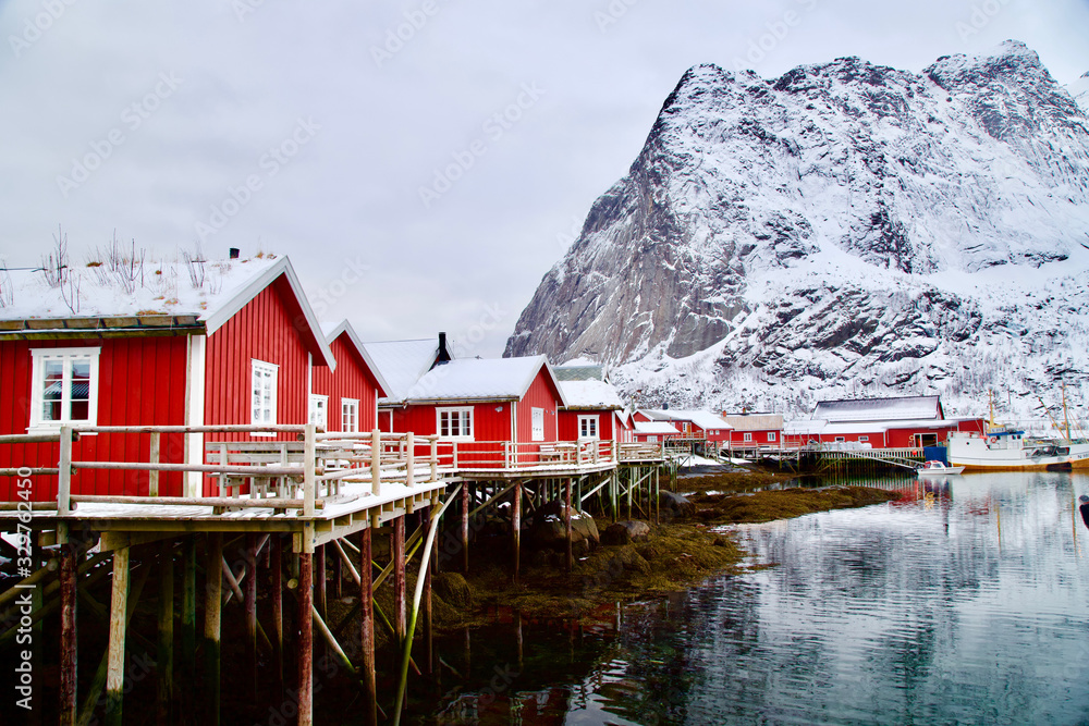 The fisherman red houses situated along the bay beside snow-capped mountains. 