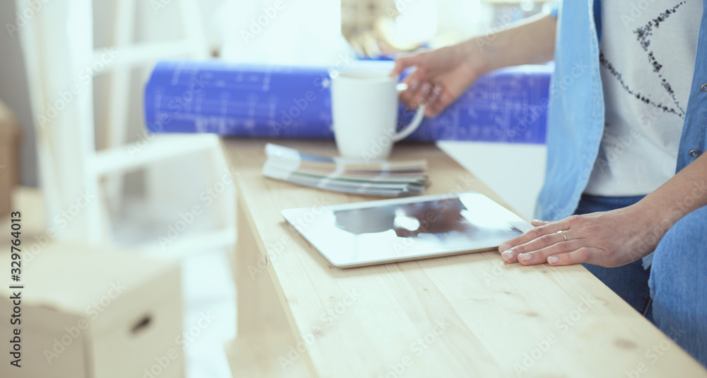 Pretty smiling woman painting interior wall of home with paint roller