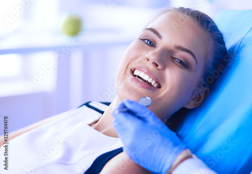 Young Female patient with open mouth examining dental inspection at dentist office.