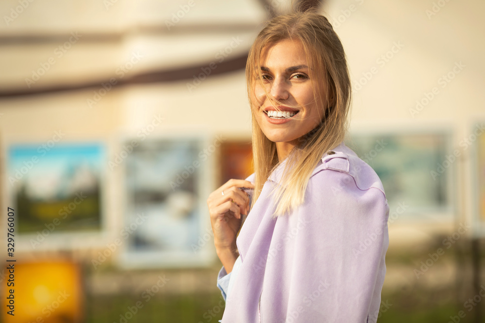 Attractive young blond woman close-up portrait. Female outdoors on spring sunshine background. Cheerful lady closeup portrait in fall time.