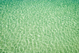 Full frame background of sparkling tropical water with wave patterns on the shallow sea bed under bright sun