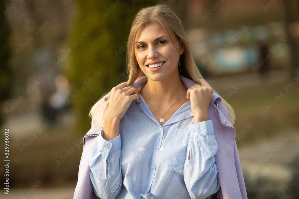Attractive young blond woman close-up portrait. Female outdoors on spring sunshine background. Cheerful lady closeup portrait in fall time. Attractive young blond woman close-up portrait. Female outdoors on spring sunshine background. Cheerful lady closeup portrait in fall time.