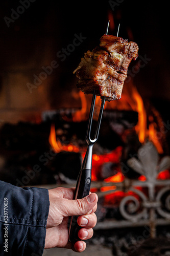 American cuisine. Fried pork ribs with honesty, chopped on a fork against a fire. The cook holds a fork in his hand. background image, copy space text