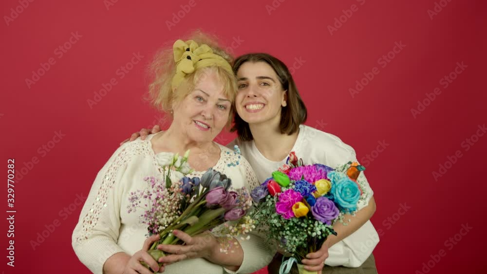 Smiling grandmother and granddaughter posing with flowers Smiling grandmother and granddaughter posing with flowers