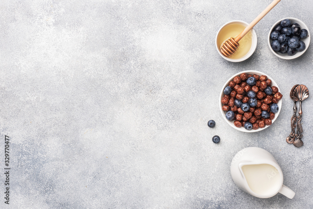 Chocolate flakes made from natural cereals with fresh blueberries, honey and milk. The concept of a healthy wholesome Breakfast. copy space Grey concrete background Chocolate flakes made from natural cereals with fresh blueberries, honey and milk. The concept of a healthy wholesome Breakfast. copy space Grey concrete background