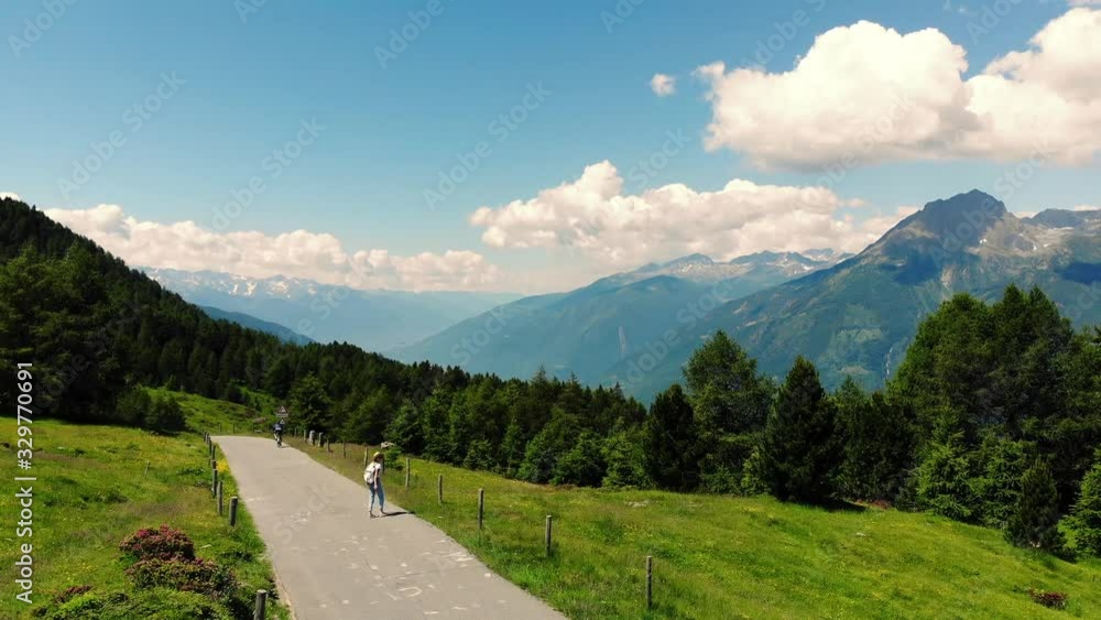 Young woman traveler in hat walking on road to destination in mountains during journey in summer, girl hiker taking pictures for blog using camera on modern cellphone Young woman traveler in hat walking on road to destination in mountains during journey in summer, girl hiker taking pictures for blog using camera on modern cellphone