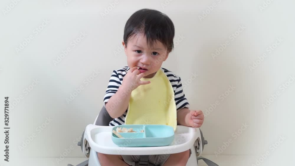 The little boy practiced eating bread placed on kid plate by himself. Adorable Kid Enjoy Eating Healthy Food. The little boy practiced eating bread placed on kid plate by himself. Adorable Kid Enjoy Eating Healthy Food.