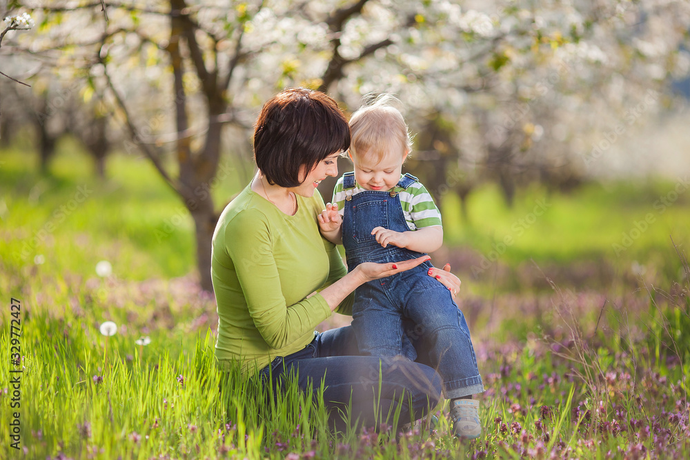 Fototapeta premium Happy woman and child in the blooming spring garden.