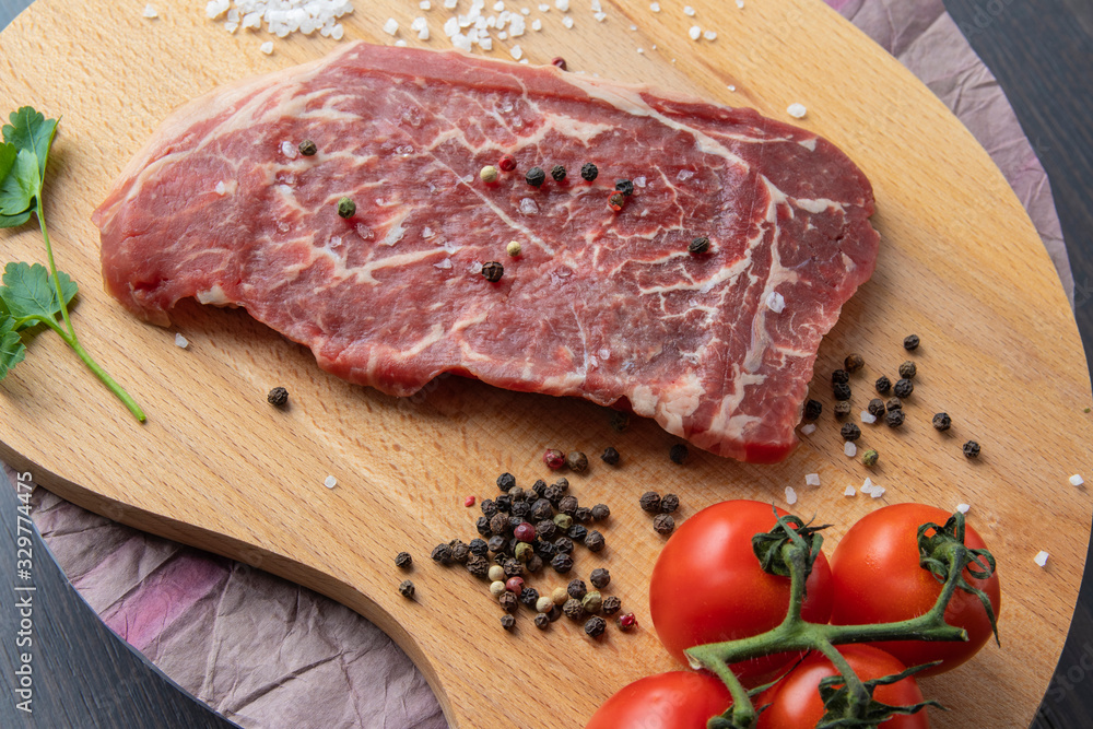 Raw beef steak with spices on a dark board. View from above. Raw beef steak with spices on a dark board. View from above.