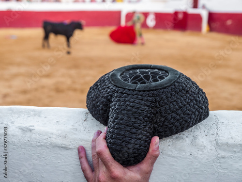 Montera sujetada por una mano en una plaza de toros durante la faena del torero photo