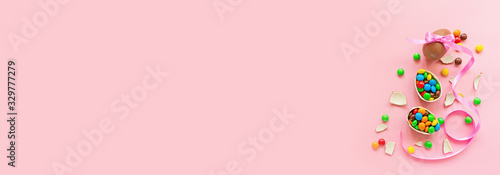 Chocolate Easter eggs and colorful candies on pastel pink paper background. flat lay, top view, overhead, copy space, template, mockup. Horizontal banner for web design © Алина Бузунова