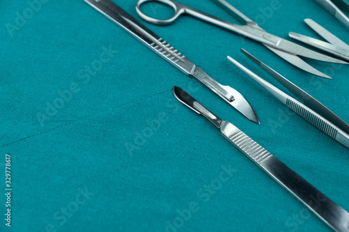 Basic surgical instrument scalpel forceps tweezers scissors spread on surgical green drape fabric © 168 Studio