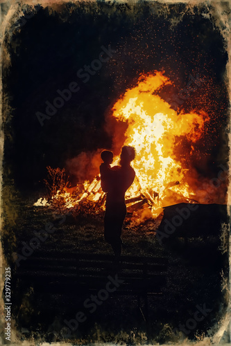 father holding his little son with burning bonfire on background, fatherhood and joy of life, old photo effect.