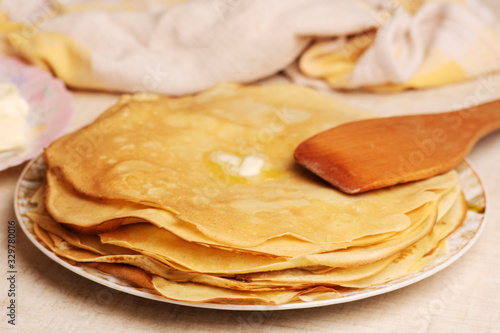 Pancakes on the white plate. Many pancakes are stacked. Thin pancakes with crispy crust. Maslenitsa. Pancakes for breakfast and carnival. Food background.