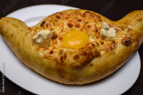 Adjarian Khachapuri on a large white plate. Tasty food close-up. photo