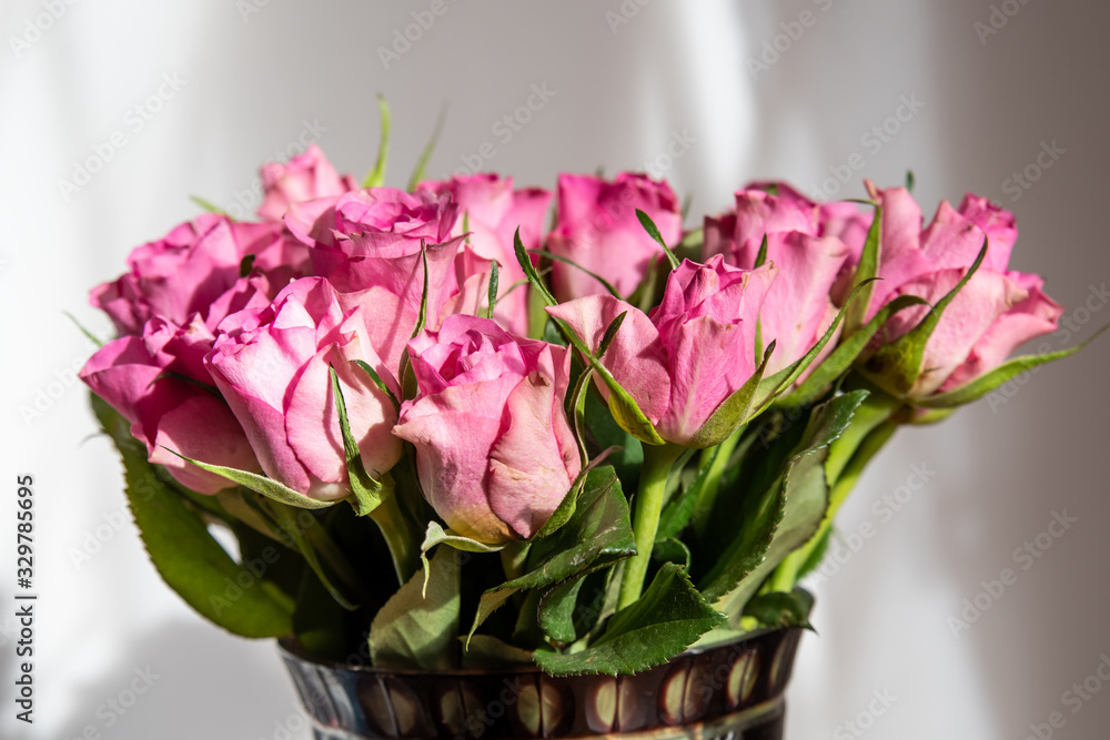Bouquet of fresh delicate light pink roses and blurred green leaves in a vase in a sunny summer day, beautiful indoor floral background Bouquet of fresh delicate light pink roses and blurred green leaves in a vase in a sunny summer day, beautiful indoor floral background