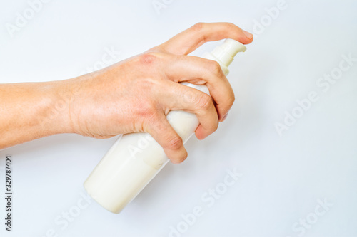 Woman hand holds bottle of soft cream against to white background. Skin care concept.