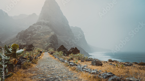 Santo Antao Island, Cape Verde. Panoramic view to Aranhas mountain peak in the valley with house ruins and stony hiking path going up the mountain from Ponta do Sol to Cruzinha village photo