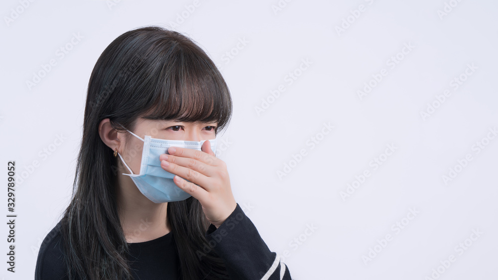 Woman coughing with mask - young Asian covering the mouth, feeling unwell with wearing medical blue face mask isolated on white background, close up. Woman coughing with mask - young Asian covering the mouth, feeling unwell with wearing medical blue face mask isolated on white background, close up.