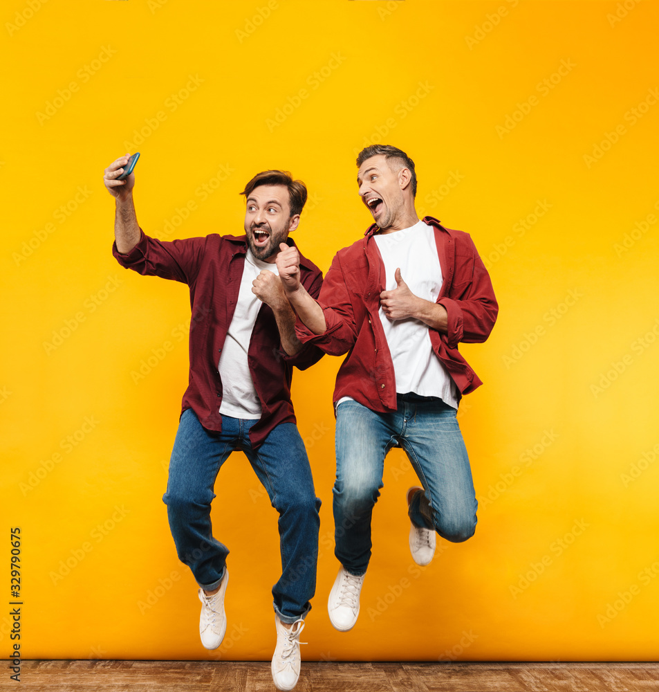 Full length image of two handsome men taking selfie photo on cellphone Full length image of two handsome men taking selfie photo on cellphone