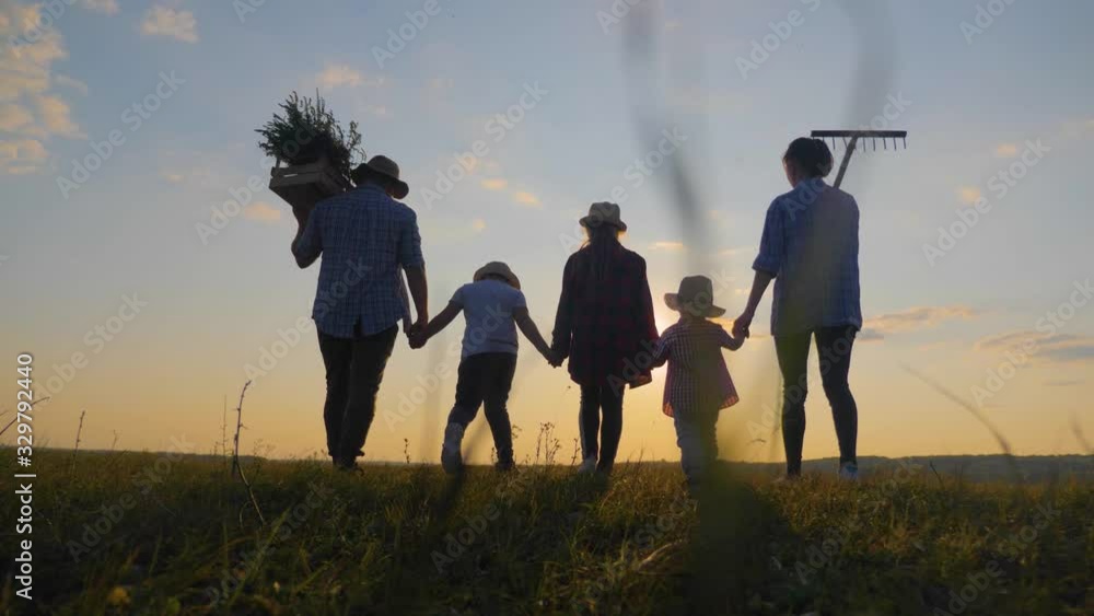 Farmers family of organic farming in the field at sunset. Teamwork in agricultural harvest farming. Concept of happy friendly family. Farmers family of organic farming in the field at sunset. Teamwork in agricultural harvest farming. Concept of happy friendly family.