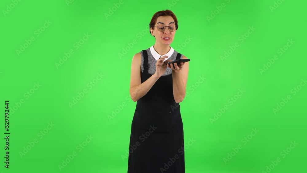 Funny girl in round glasses is asking for information on the network via phone and shocked. Green screen Funny girl in round glasses is asking for information on the network via phone and shocked. Green screen