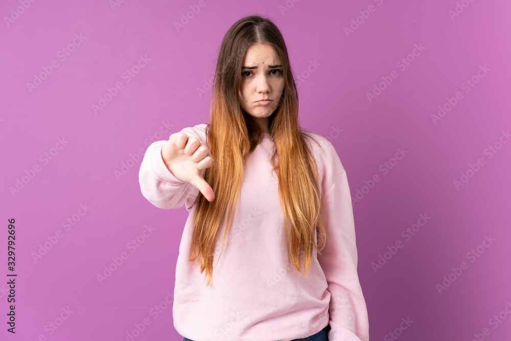 Young caucasian woman isolated on purple background showing thumb down with negative expression Young caucasian woman isolated on purple background showing thumb down with negative expression