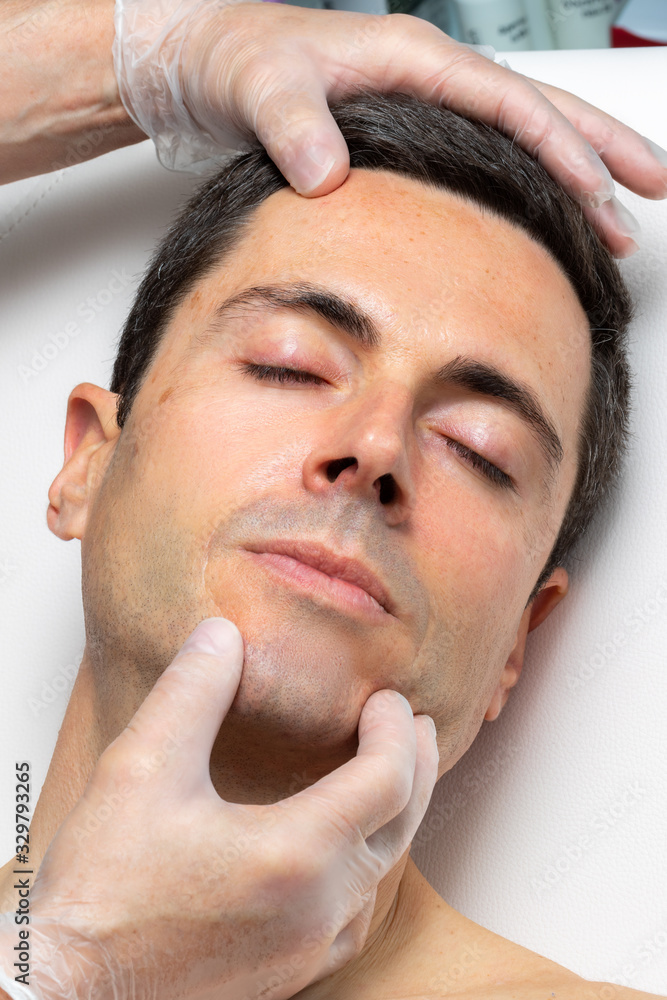 Obraz premium Hands with medical exam gloves inspecting middle aged male face.